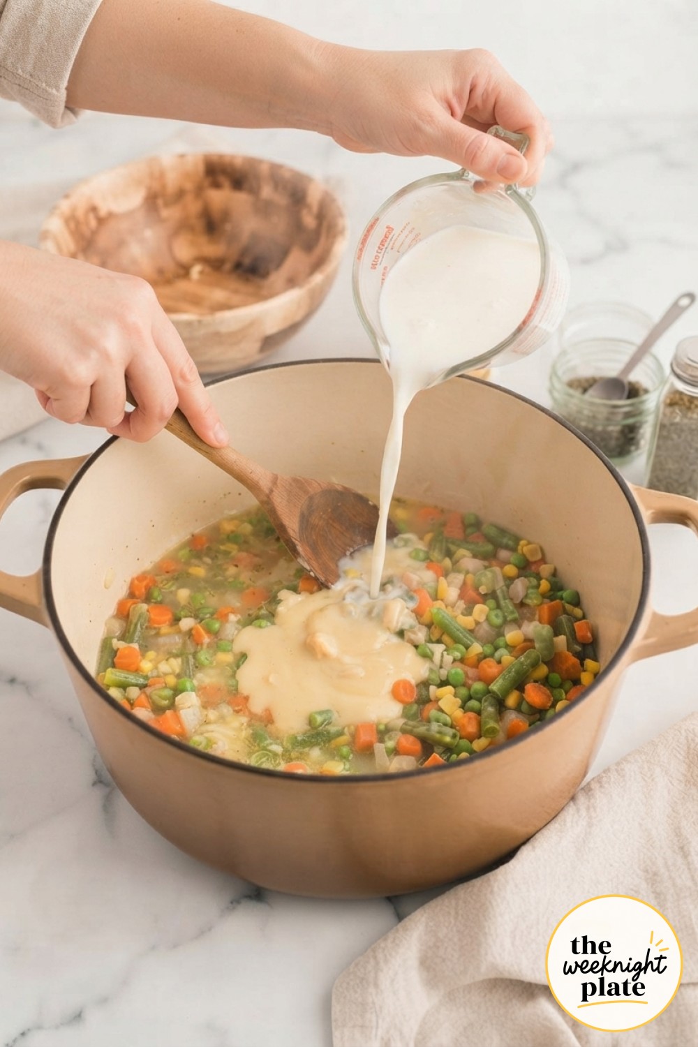 Pouring milk and broth into the pot while stirring in cream of chicken soup for a creamy pot pie soup base