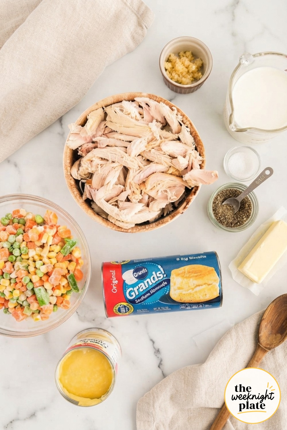 Raw ingredients for chicken pot pie soup laid out, including shredded chicken, frozen vegetables, and biscuits