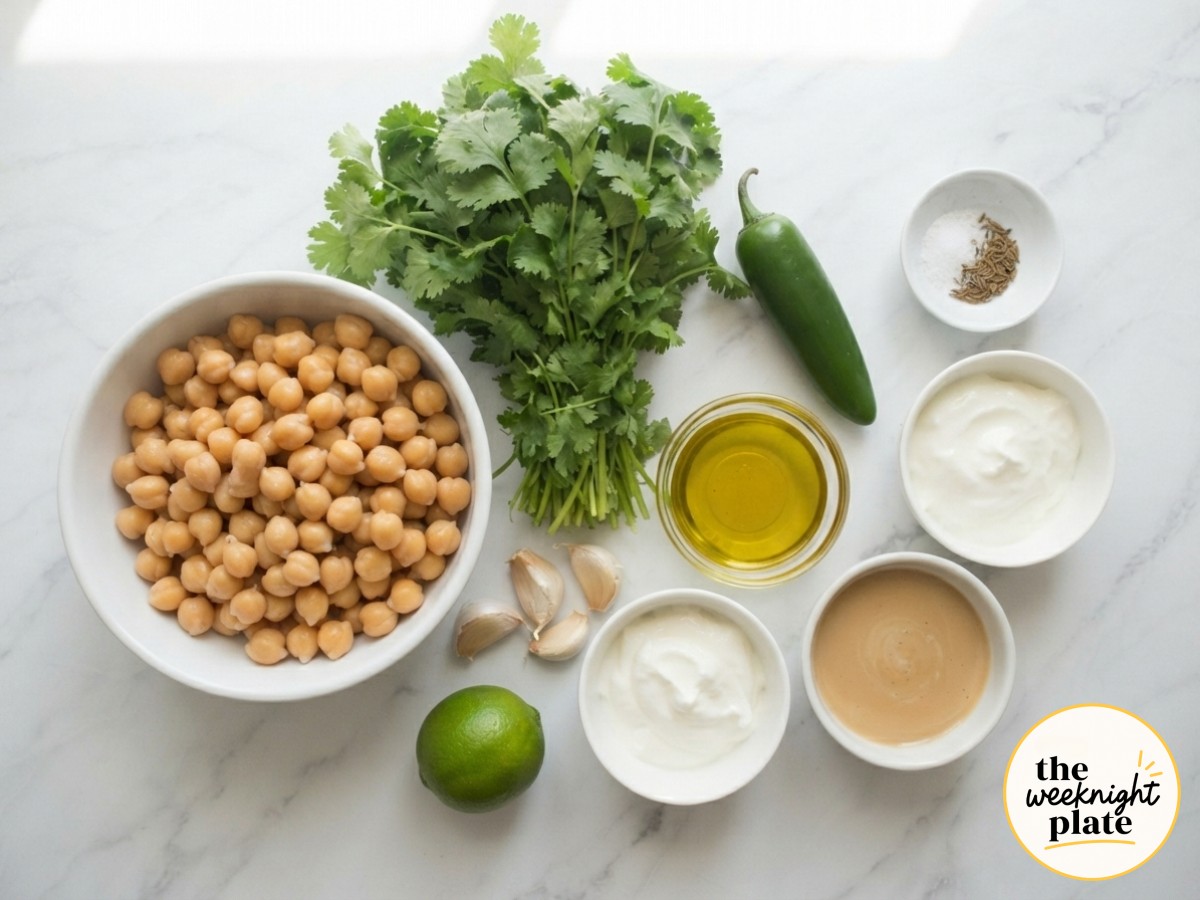 Raw ingredients for a mediterranean hummus bowl arranged on marble before any chopping begins